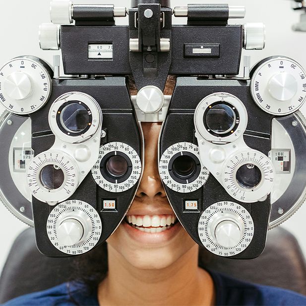 Mujer sonriente mirando a través de un foróptero. 