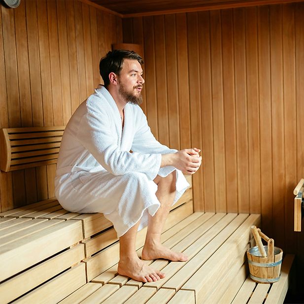 chico sentado en sauna con albornoz 