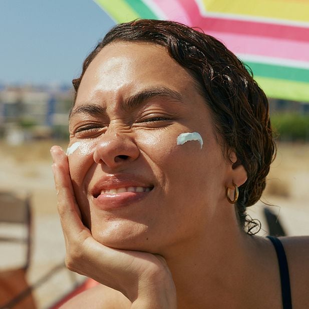 chica en la playa con crema solar en la cara 