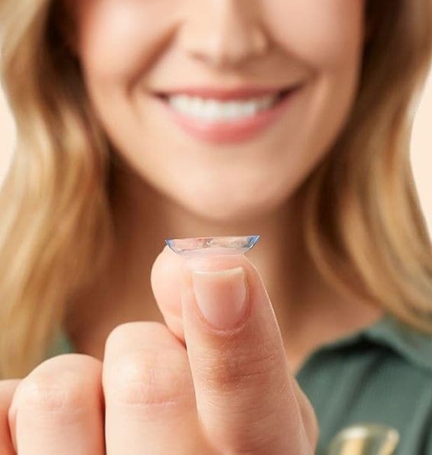 Chica sonriente con lentilla en el dedo