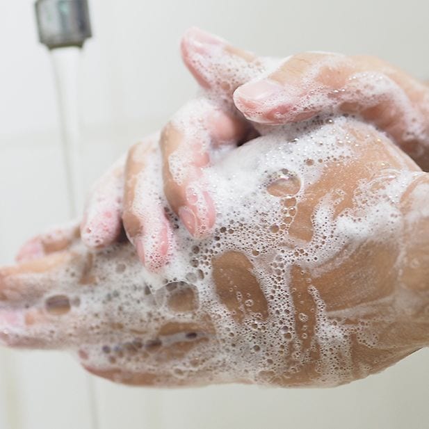 Primer plano de manos lavándose con espuma de jabón 