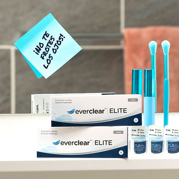 Post-it en un espejo con el mensaje «No te frotes los ojos», junto a envases de everclear ELITE y productos de maquillaje