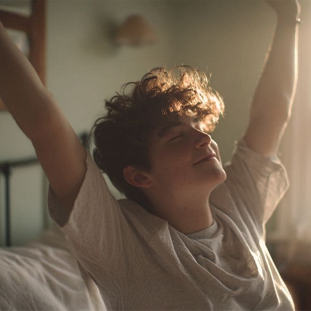 Niño despertándose, estirando los brazos y sonriendo