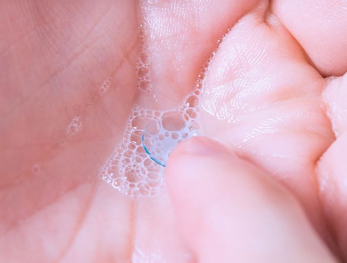 Lentes de contacto en los dedos junto al lavabo